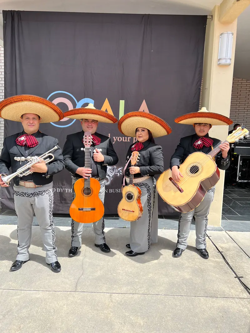 Cuatro integrantes del mariachi con traje gris y sombrero, con trompeta y guitarras, en un evento en Ocala