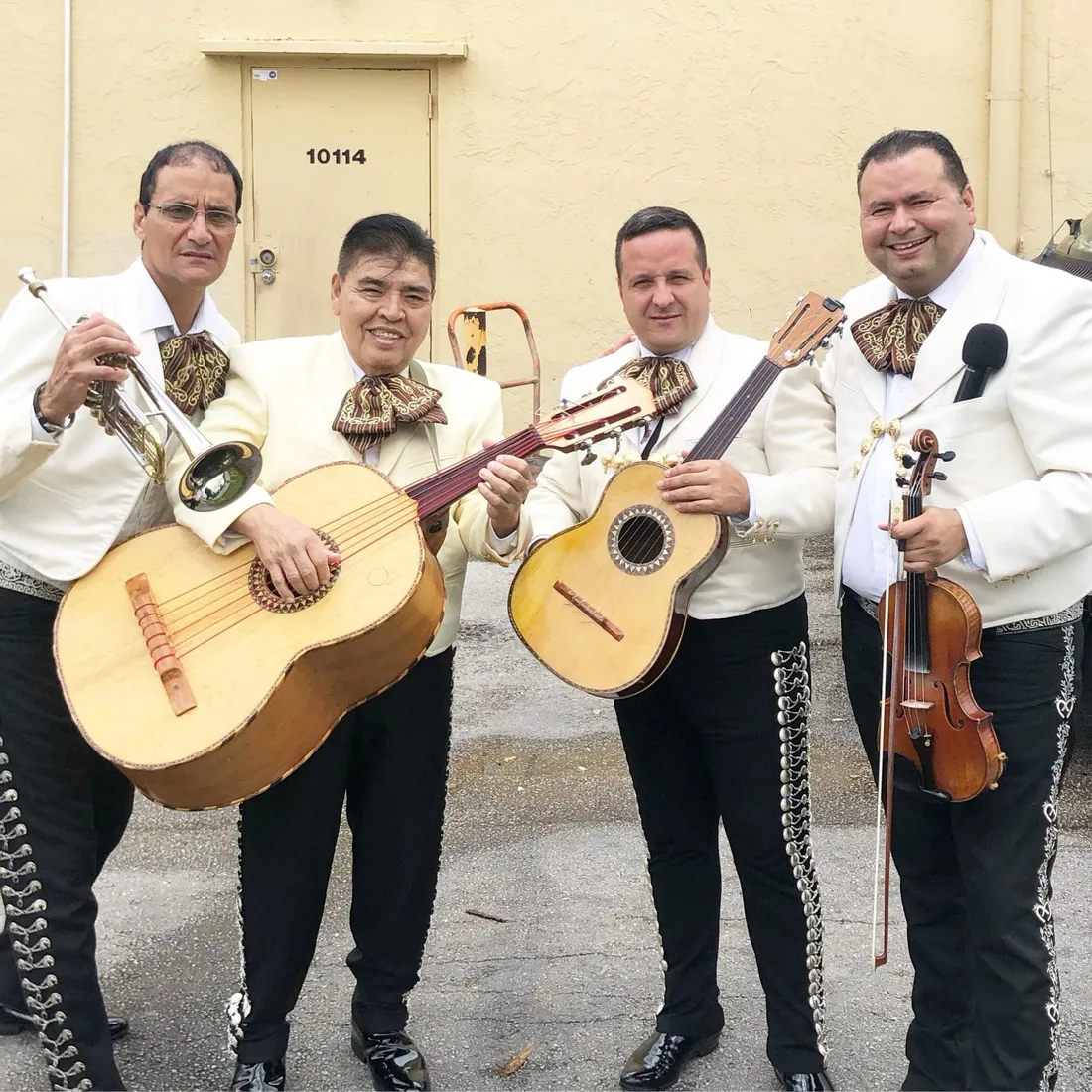 Cuatro músicos de Mariachi America Canta con guitarrón, vihuela, guitarra, trompeta y violín
