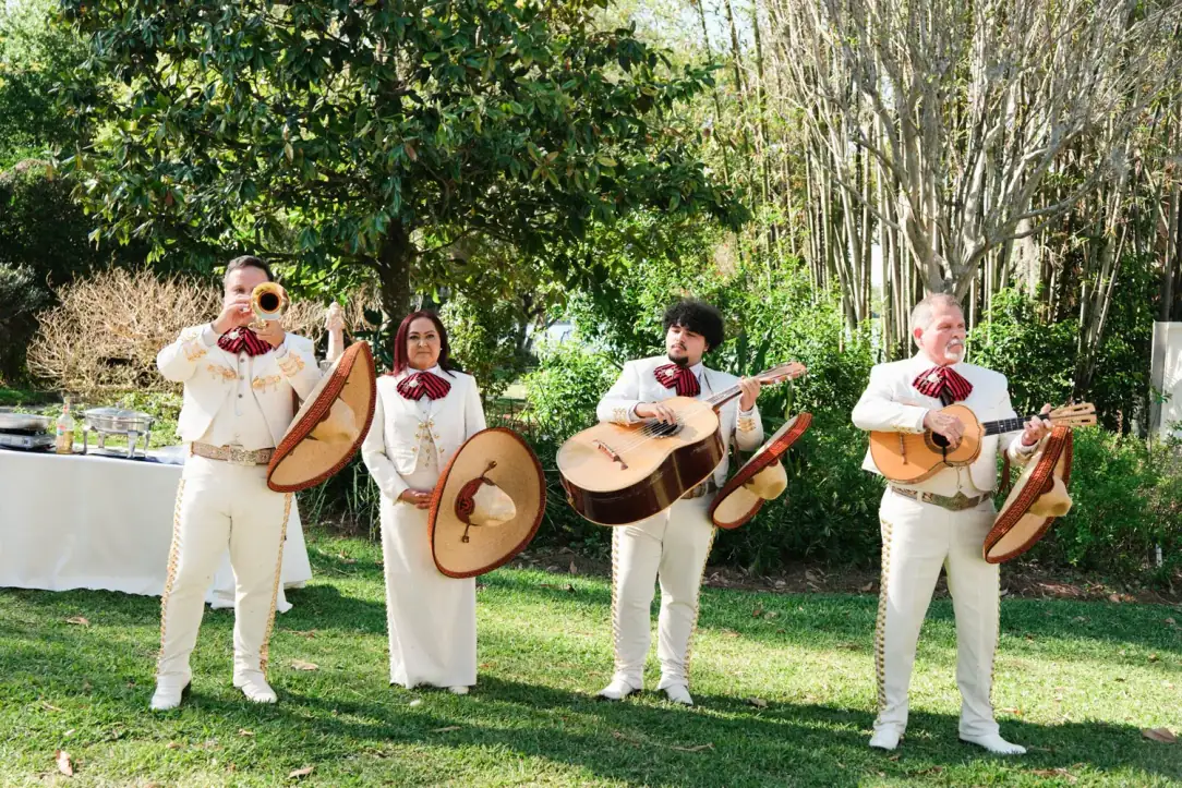 Mariachi America Canta con traje claro tocando una serenata en el jardín de una casa