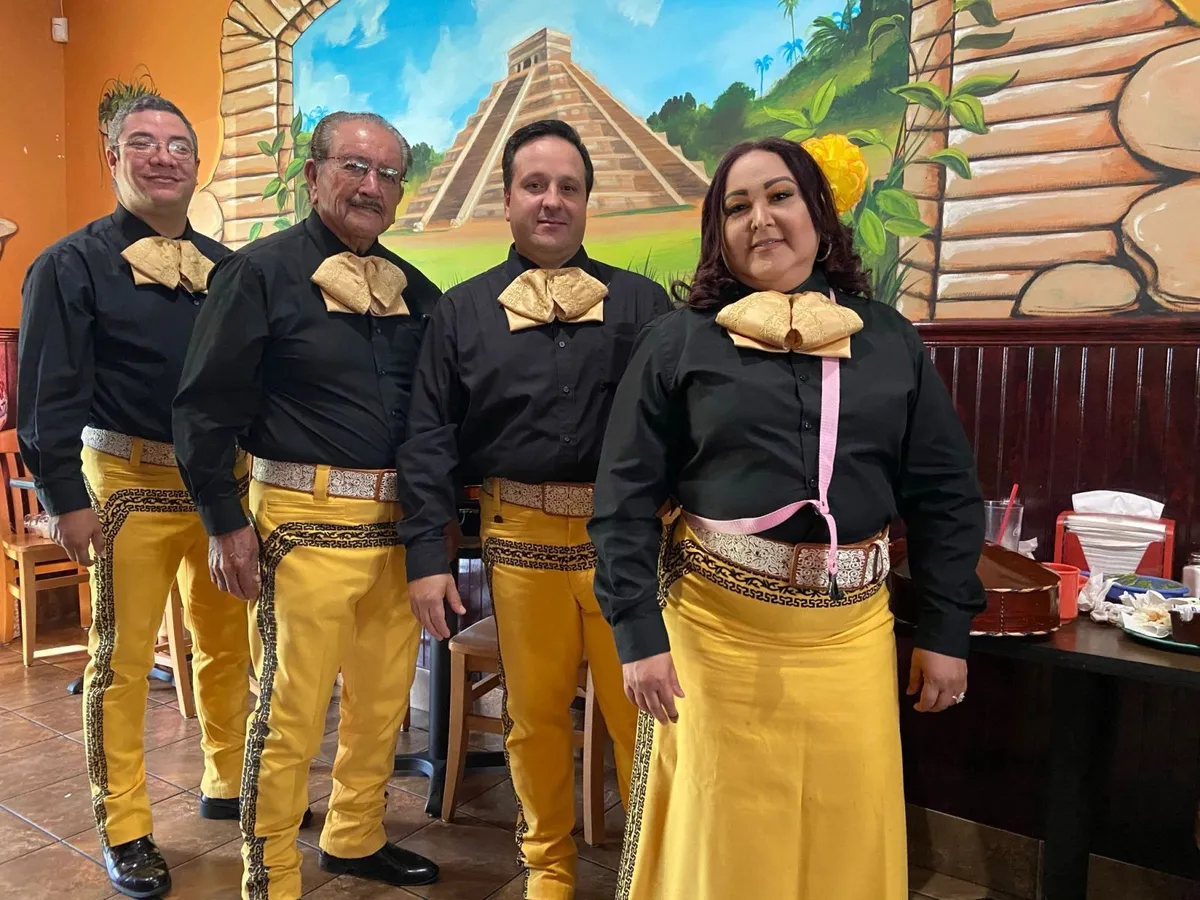 Mariachi America Canta con trajes negros y dorados en un restaurante mexicano para un cumpleaños