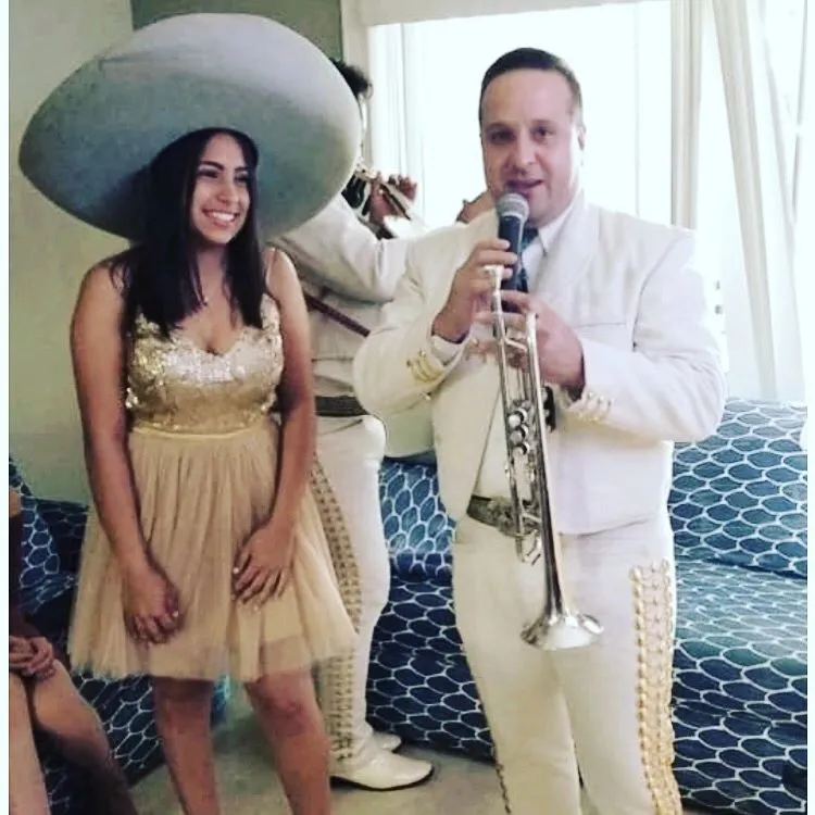 Quinceañera con sombrero de charro junto al trompetista de Mariachi America Canta