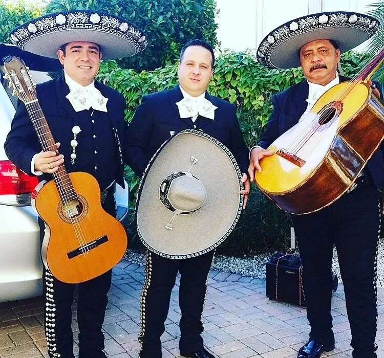 Tres músicos de mariachi con traje de charro negro, guitarra, vihuela y sombrero